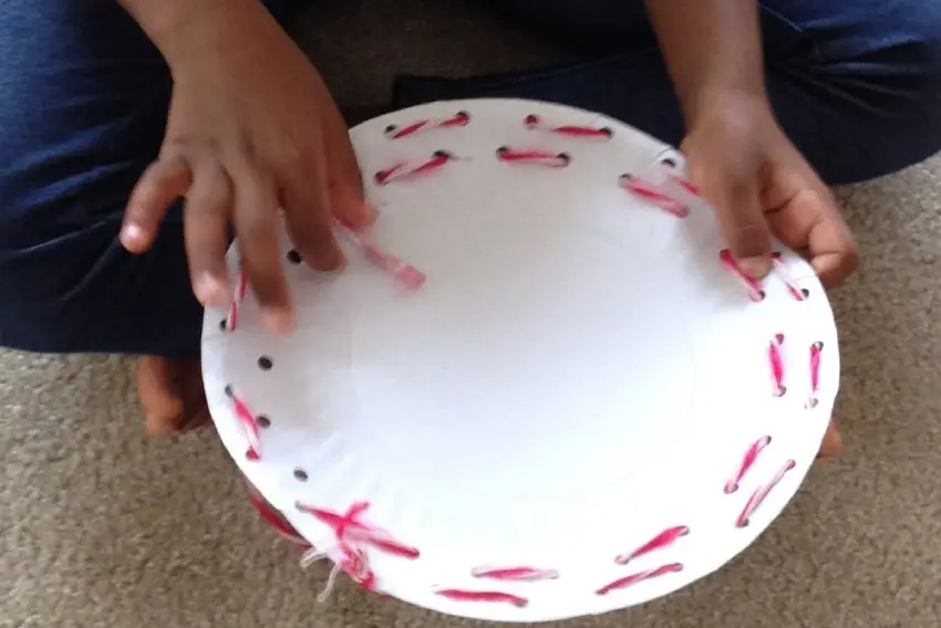 A person holding onto a paper plate with red string on it